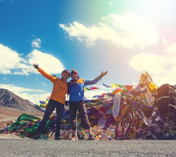 Young,Happy,Friends,Cyclists,Standing,On,Road,In,Himalayas,Mountains