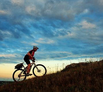 Silhouette of a biker and bicycle on sky background
