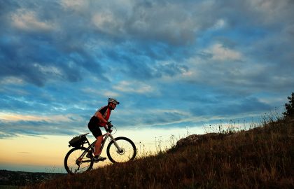 Silhouette of a biker and bicycle on sky background